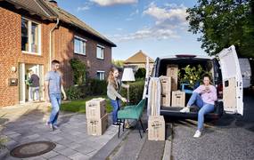 Mehrere Personen tragen Umzugskartons und beladen ein Fahrzeug.