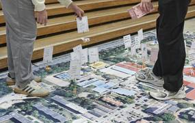 Auf einer großen Planvorlage bewegen Hände verschiedene Aufsteller