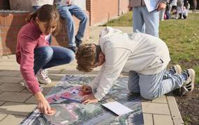 Zwei Kinder tragen Informationen auf einen Lageplan eines Schulgeländes zusammen