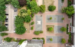 Ein Bild des Marktplatztes von oben. Man sieht den Brunnen, die Grünflächen und eine Fußballfläche.
