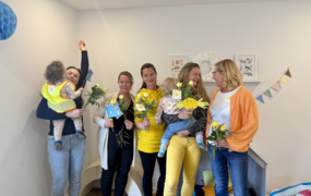 Fünf Frauen stehen gut gelaunt nebeneinander. Zwei von ihnen haben ein Kleinkind auf dem Arm.