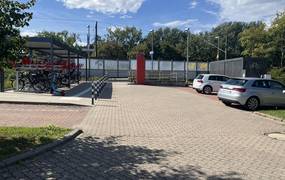Parkplatz mit zwei Autos und der Park Und Ride Station mit Fahrrädern.
