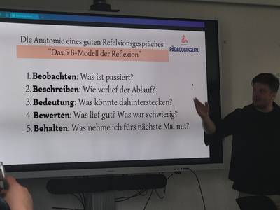 Auf dem Whiteboard sieht man eine Folie mit dem 5B Modell der Reflexion.