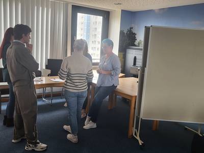 5 Fachkräfte stehen im Kreis an einem Arbeitstisch und besprechen eine Aufgabe.