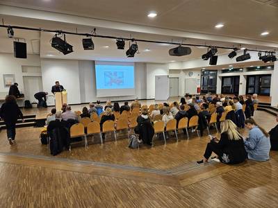 Menschen, die im Forum auf Stühlen sitzen.