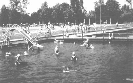 Schwarz weiß Fotografie mehrerer Schwimmbecken, in denen sich zahlreiche Schwimmer aufhalten.