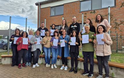 Die Teilnehmenden stehen im Halbkreis und zeigen ihre Teilnahmebescheinigung