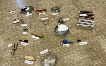 In der Mitte des Bodens liegen Orff- Instrumente. Diese sind speziell für die musikalische Früherziehung entwickelt wurden.