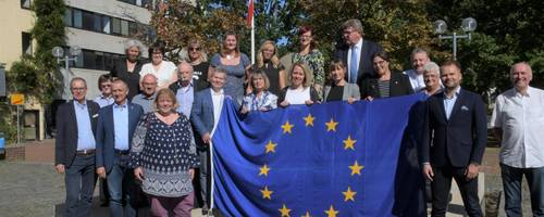 Die Delegationen zum Gruppenphoto auf dem Fritz-Willig-Brunnen vor dem Rathaus mit Europafahne