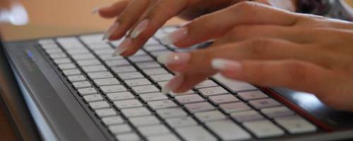 Es sind zwie Frauenhände zursehen, die auf einer Laptoptastatur tippen.