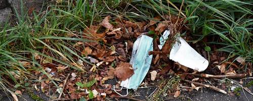 Eine Maske und ein Einwegbecher am Straßenrand