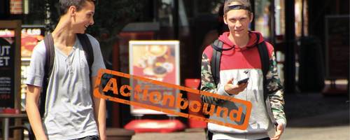 Zwei Jungen laufen nebeneinander und haben ihre Handys in der Hand