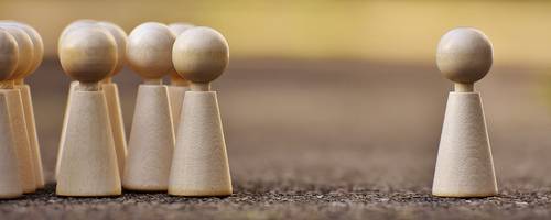 Spielfiguren stehen sich gegenüber. Auf der einen Seite eine Grußße, auf der anderen Seite eine einzelne Spielfigur.