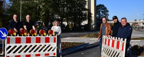 Sechs Personen stehen an einer Barke und öffnen diese. Dahinter sieht man eine Straße.