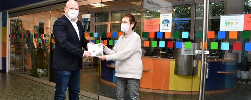 Der Bürgermeister überreicht einer Mitarbeiterin die neue Bürgerbroschüre.