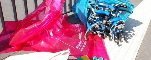 Rote Müllsäcke und blaue Greifzangen auf einem Tisch.