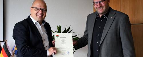 Ein Mann gibt einem anderen Mann eine Urkunde.