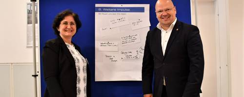 Ein Mann und eine Frau stehen vor einer Pinnwand.