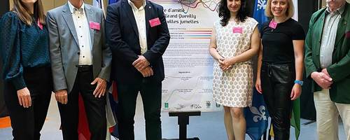 Eine Gruppe von Frauen und Männern stehen links und recht von einer Urkunde.