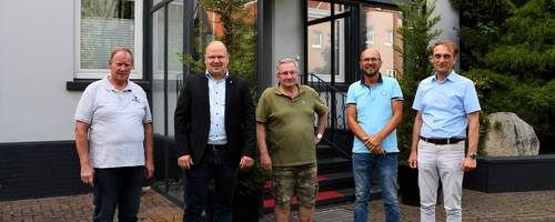 Fünf Männer stehen vor einem Hauseingang.