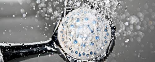 Duschkopf von unten fotografiert. Aus dem Kopf kommt Wasser.