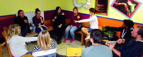 Eine Gruppe Jugendlicher sitzt auf Sofas und spielen ein Spiel.