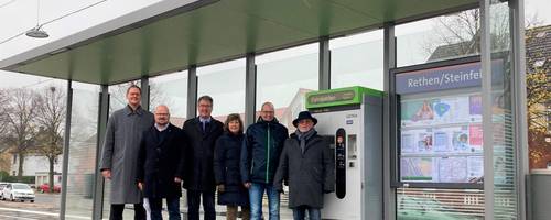 Eine Personengruppe steht auf einem Hocbahnsteig.
