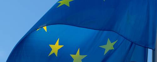 Die Flagge der EU weht im Wind vor einem blauen Himmel.