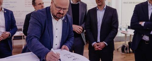 Ein Mann beugt sich über ein Dokument und unterschreibt dieses.