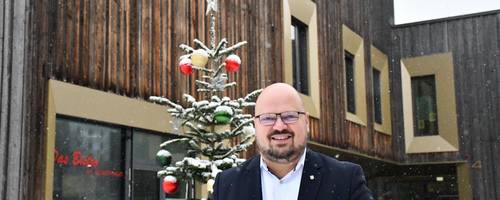 Bürgermeister Kai Eggert steht vor einem schneebedeckten Weihnachtsbaum