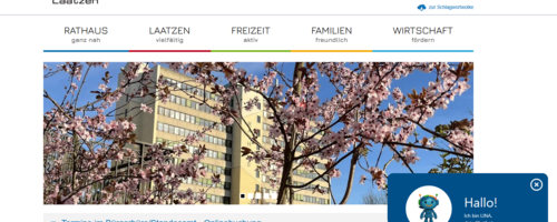 Ein Bild der Homepage mit einem kleinen Fenster, in dem der Chatbot LINA zu sehen is. LINA ist eine kleine roboterähnliche Figur.