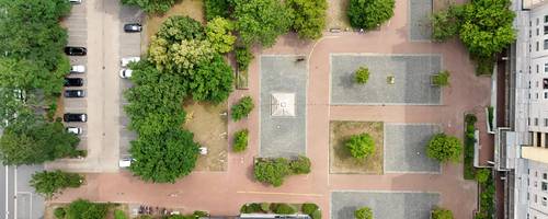 Ein Bild des Marktplatztes von oben. Man sieht den Brunnen, die Grünflächen und eine Fußballfläche.