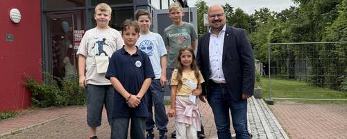 Kinder und ein Mann stehen vor einem Gebäude auf Stufen.