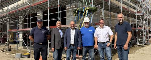 Eine Gruppe steht bei sonnigem unter einem Richtkranz.