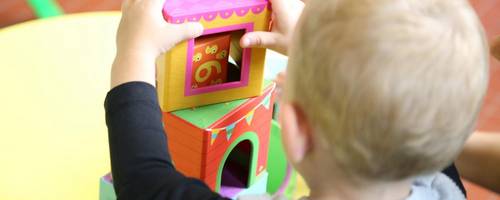 Kind in Rückenansicht spielt mit Bauklätzen