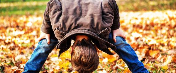 Junge steht auf einer Wiese, auf der Herbstlaub liegt ©Ilka Hanenkamp-Ley