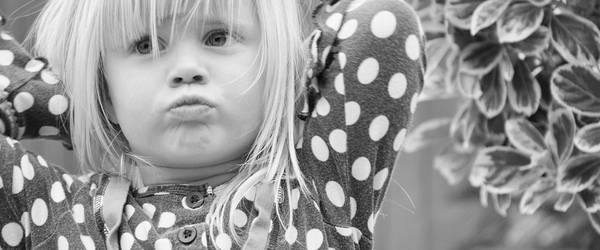 Ein Mädchen verschränkt die Arme hinter dem Kopf und schaut schmollend.