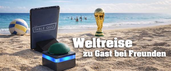 Tablet und Buzzer stehen am Strand vor dem Meer, im Hintergrund sind Menschen im Meer, ein Volleyball und der WM Pokal stehen am Strand