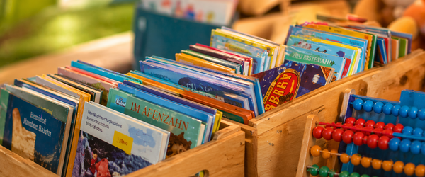 verschiedene Bücherkisten, ein Abakus lehnt davor