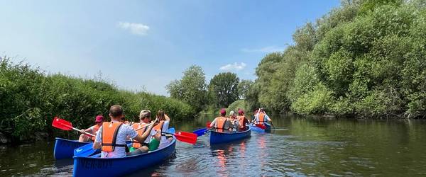 Kanuboote mit Personen besetzt, die auf einem Fluss fahren
