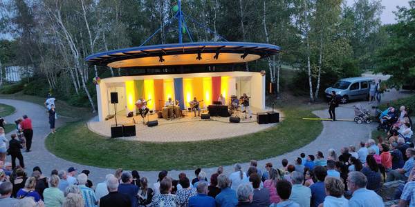 Blick von der vollbesetzten Tribüne der Kulturbühne im Park der Sinne  auf ein Konzert